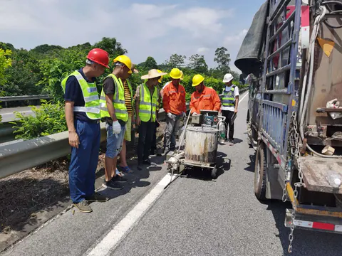 Crew applying a white thermoplastic centerline on a mountain expressway