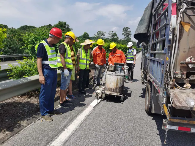 Crew applying a white thermoplastic centerline on an expressway