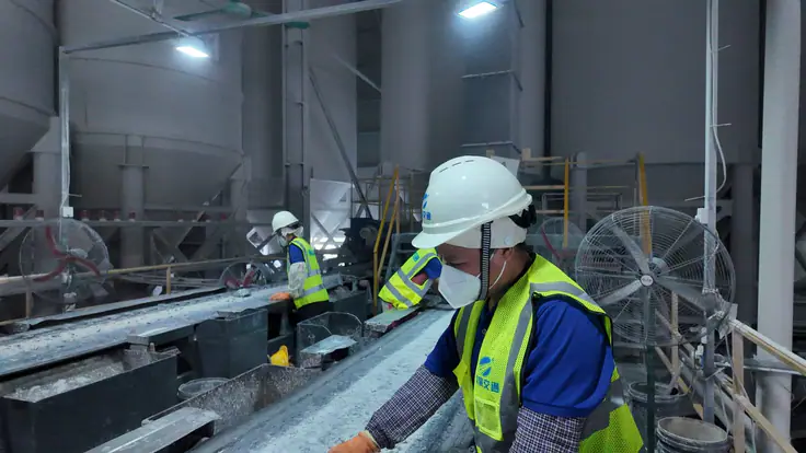 Crew inspecting a conveyor line beneath the raw-material silos