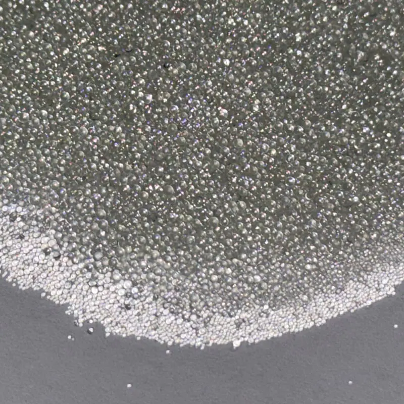 Pile of AASHTO M247 Type 1 reflective glass beads sparkling under daylight